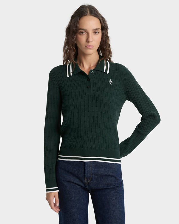 Woman wearing a green ribbed sweater with white trim on a light gray background
