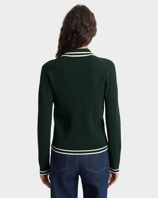 Person wearing a green sweater with white trim on a plain background