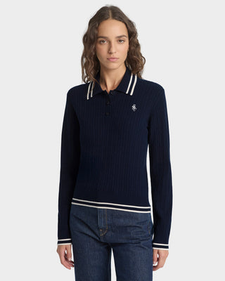 Woman wearing a navy sweater with white trim on a white background