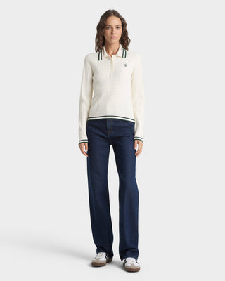 Woman wearing a white sweater and dark blue jeans on a white background