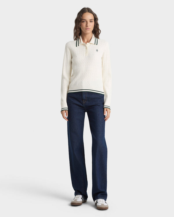 Woman wearing a white sweater and dark blue jeans on a white background