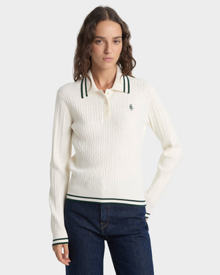 Woman wearing a white ribbed sweater with black trim on a light gray background