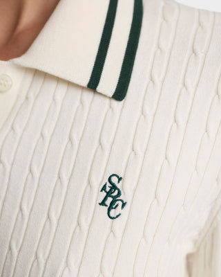 Close-up of a cable-knit garment with a logo on a white background