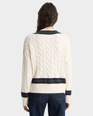 Person wearing a cream sweater with black trim on a white background