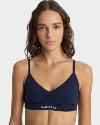 Woman wearing a navy blue sports bra with 'Sporty&Rich' logo on a white background