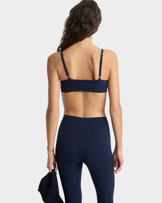 Person wearing a navy blue sports bra and leggings on a white background