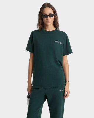 Person wearing a green t-shirt and pants with a brand logo on a white background