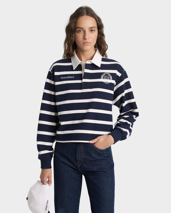 Person wearing a navy and white striped rugby shirt with a brand logo on a white background