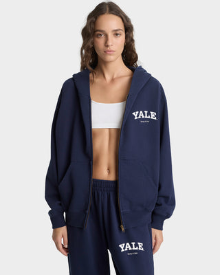 Person wearing a navy Yale hoodie and sweatpants on a white background