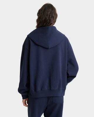 Person wearing a navy blue hoodie and pants on a white background