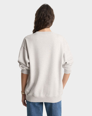 Person wearing a light gray sweater and blue jeans on a white background
