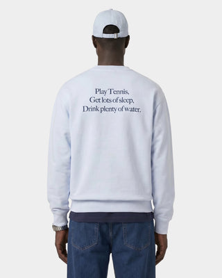 Person wearing a light gray sweatshirt with text on the back, standing against a white background