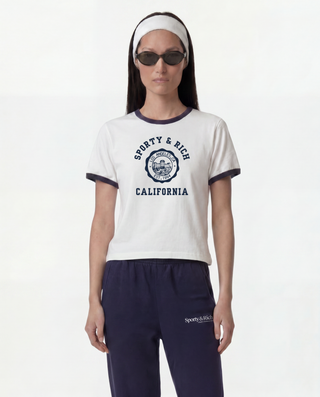 Woman wearing a white t-shirt with 'Sworty & Rich California' text and navy pants on a white background