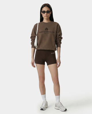 Woman wearing a brown sweatshirt and shorts with a logo on a white background