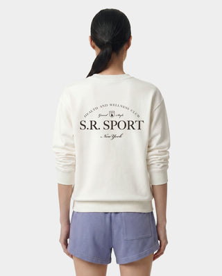 Person wearing a white sweatshirt with 'S.R. Sport' branding on a plain background