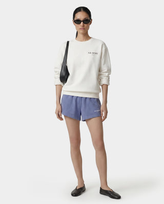 Person wearing a white sweatshirt and blue shorts on a white background
