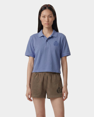 Woman wearing a blue polo shirt and brown shorts with a logo on a white background