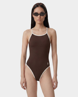 Woman wearing a brown swimsuit with white trim on a white background