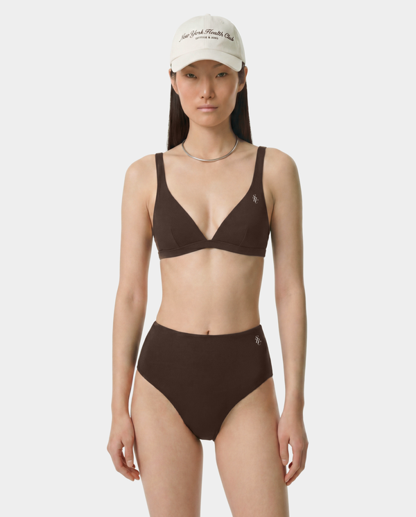 Woman wearing a brown bikini set with a white cap on a white background