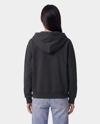 Person wearing a black hoodie and light blue jeans on a white background