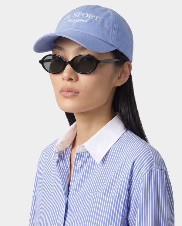 Person wearing a blue cap and sunglasses with a white background