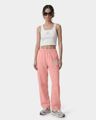 Woman wearing a white tank top and pink sweatpants on a white background