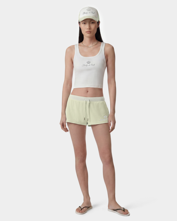 Woman wearing a white tank top and light green shorts on a white background