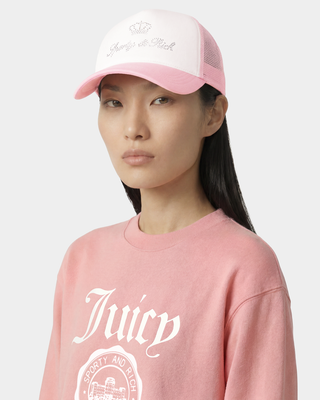woman wearing a pink 'Juicy' sweatshirt and cap on a light gray background