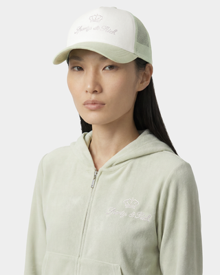 Person wearing a light green hoodie and cap with branding on a white background