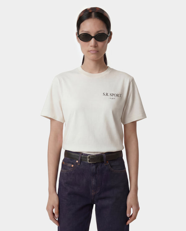Person wearing a white t-shirt with 'S.R. Sport' logo and dark jeans on a white background