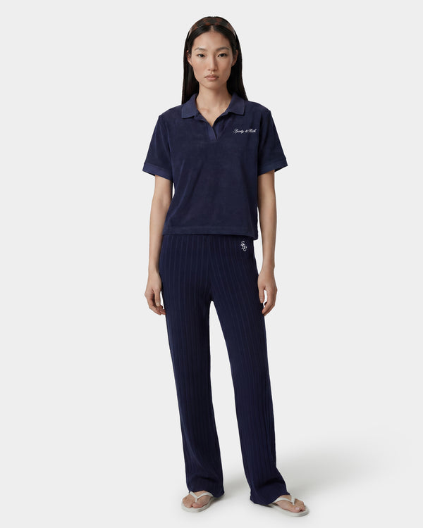 Woman wearing a navy blue polo shirt and pants on a white background