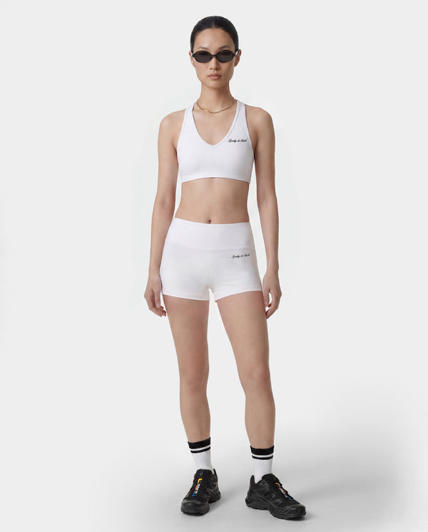 Person wearing a white sports bra and shorts set on a plain background