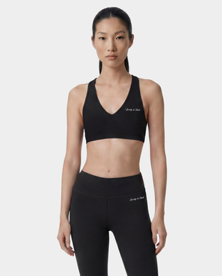 Woman wearing a black sports bra and leggings with branding on a white background