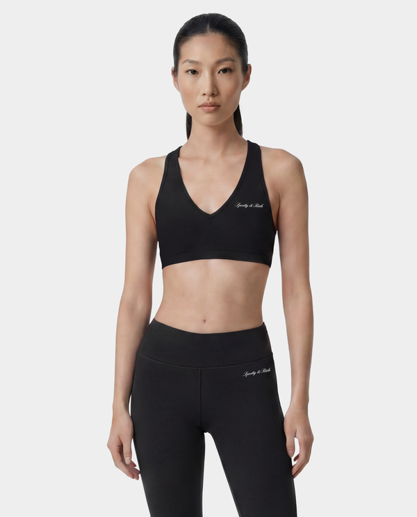 Woman wearing a black sports bra and leggings with branding on a white background