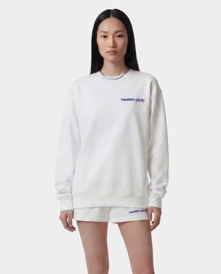 Person wearing a white sweatshirt and shorts with 'health club' branding on a white background