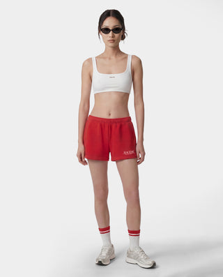 Person wearing a white sports bra and red shorts on a white background
