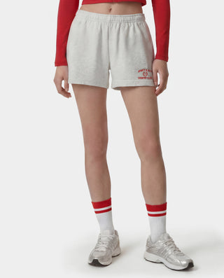Person wearing gray shorts with a logo, red long-sleeve top, white socks with red stripes, and white sneakers on a white background.