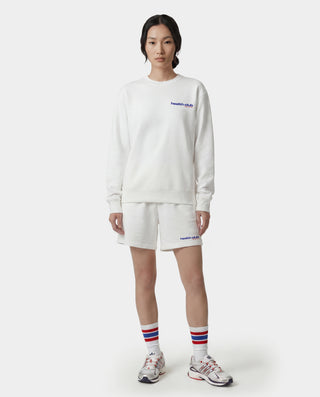 Person wearing a white sweatshirt, shorts, and socks with a brand logo on a white background