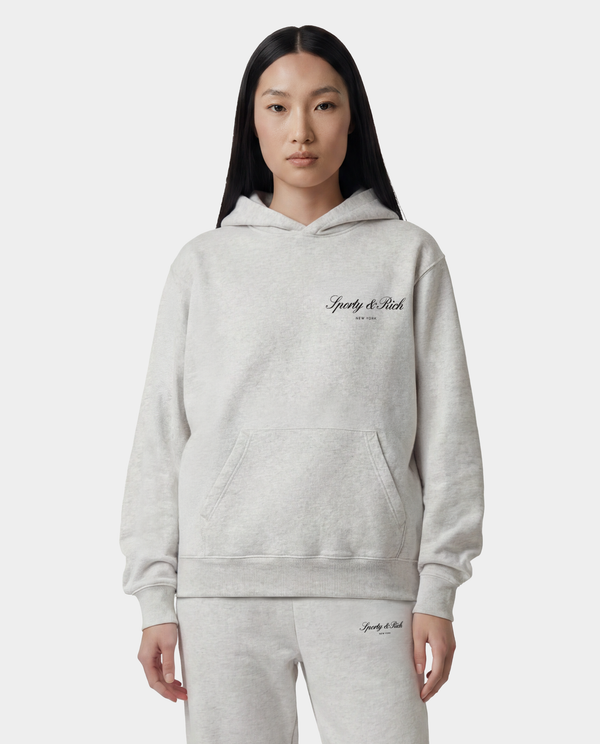 Person wearing a gray hoodie with a brand logo on a white background