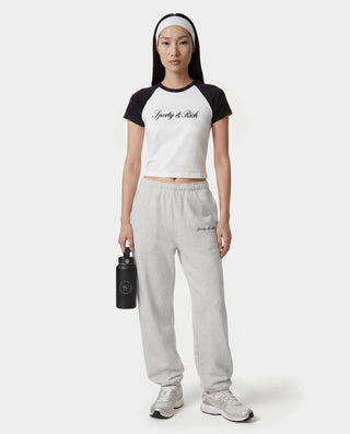 Person wearing a black and white t-shirt and gray sweatpants with a brand logo, holding a black water bottle on a white background.