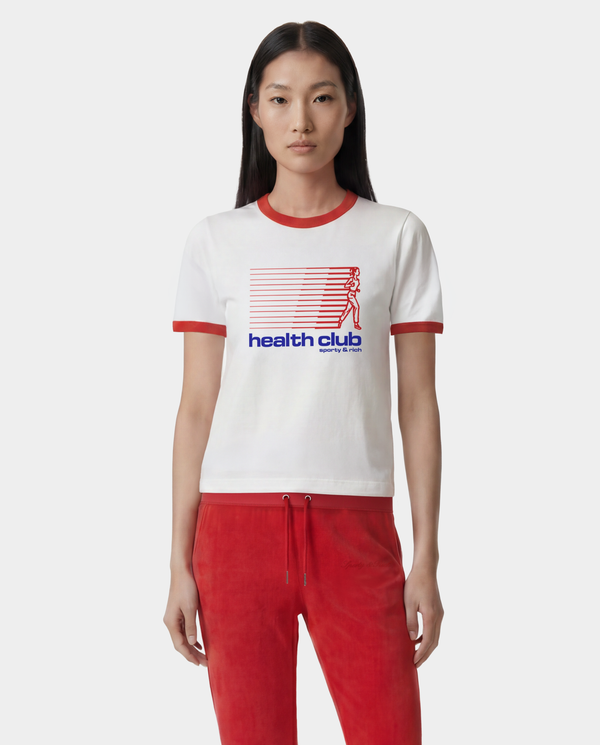 Person wearing a white t-shirt with red trim and 'health club' logo, paired with red pants on a white background