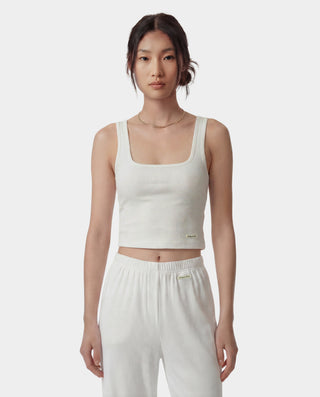 Woman wearing a white tank top and pants on a plain background