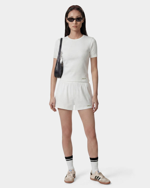 Person wearing a white outfit with black accessories on a white background