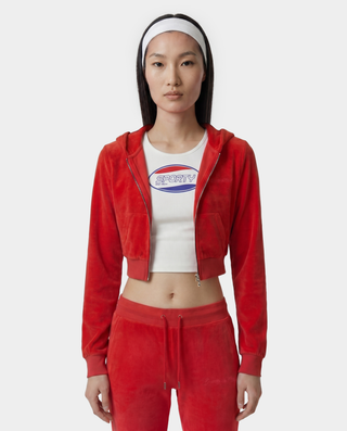 Person wearing a red tracksuit with a white crop top featuring a logo on a white background