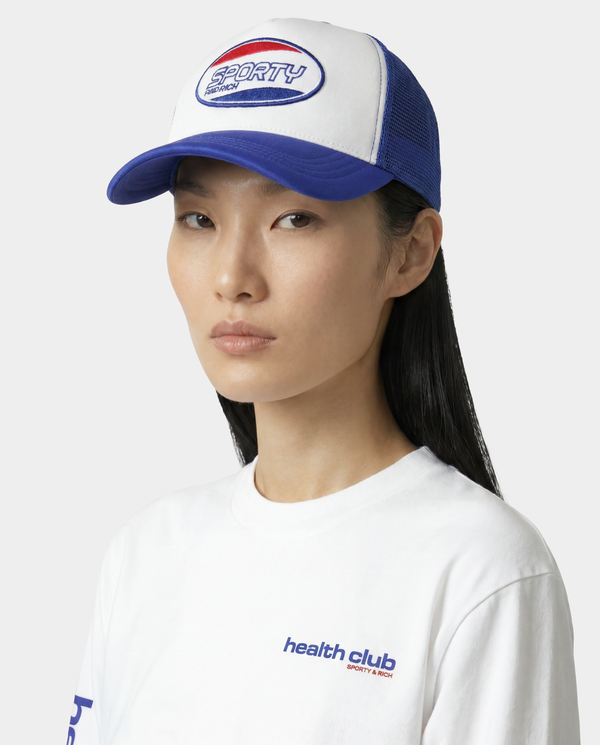 Person wearing a blue and white cap and white shirt with branding on a white background