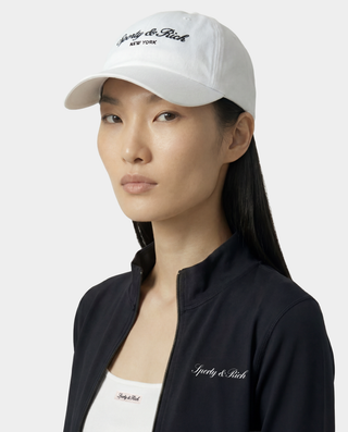 Woman wearing a white cap and black jacket with 'Sergio & Rich' branding on a white background