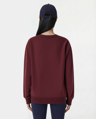Person wearing a burgundy sweatshirt and navy cap on a white background