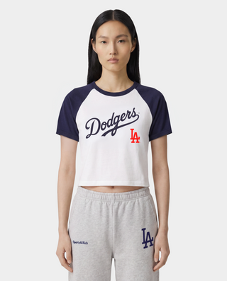 Dodgers Serif Baby Baseball Tee in White, Dark Navy, and Fire Red—crafted from 100% cotton, this stylish cropped raglan shirt features bold Dodgers text and a red LA logo on the front.