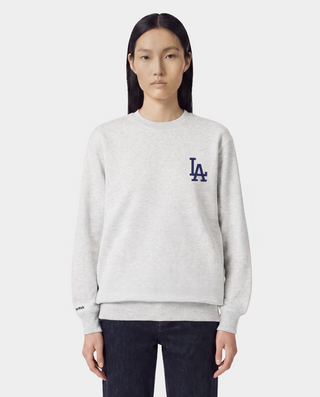 The LA Serif Crewneck in Heather Gray/Navy is a light gray crewneck sweatshirt featuring a classic navy blue LA logo on the left chest. Crafted from 100% cotton, this oversized-fit sweatshirt combines comfort and style, and is showcased against a white background.