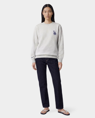The LA Serif Crewneck in Heather Gray/Navy is a light gray crewneck sweatshirt featuring a classic navy blue LA logo on the left chest. Crafted from 100% cotton, this oversized-fit sweatshirt combines comfort and style, and is showcased against a white background.